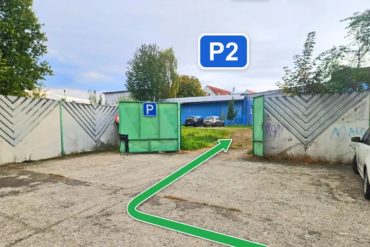 Otvorená zelená brána so značkou P, šípka vedie cez bránu na nové parkovisko P2